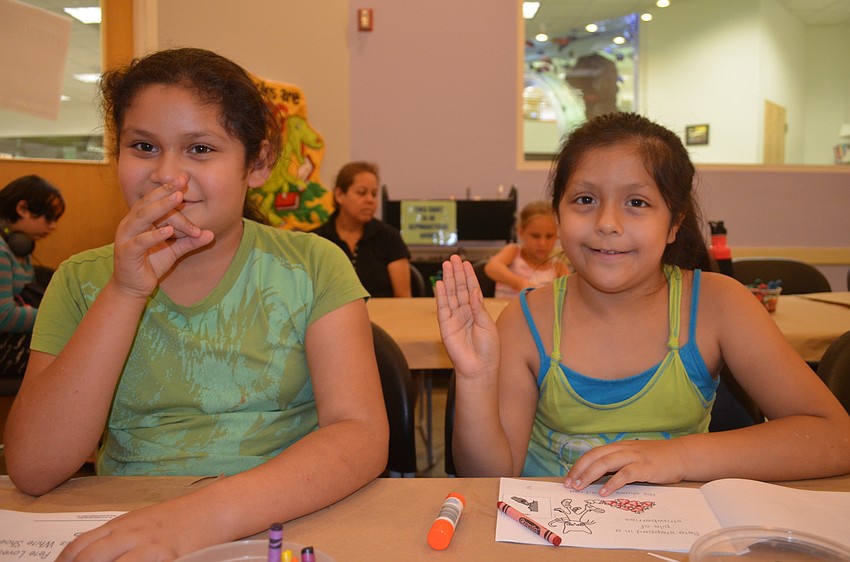 Sisters Rosa and Priscilla Hernandez sign â€œorangeâ€ and â€œblue.â€