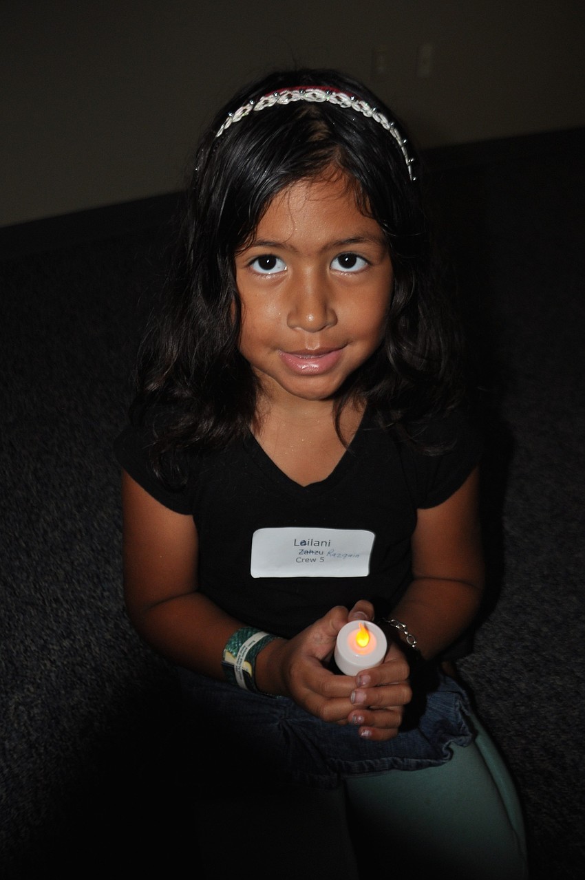 Leilani Razguin, 5, holds a candle as she tries to escape the persecution of Saul, during an interactive Bible lesson.
