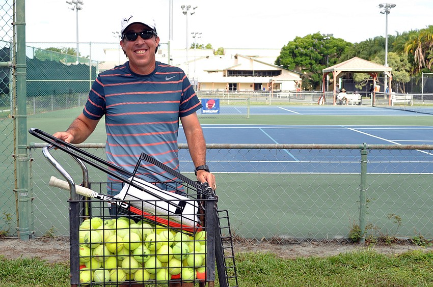 Tennis pro Alberto Layrisse wheels a basket of tennis balls to the courts.