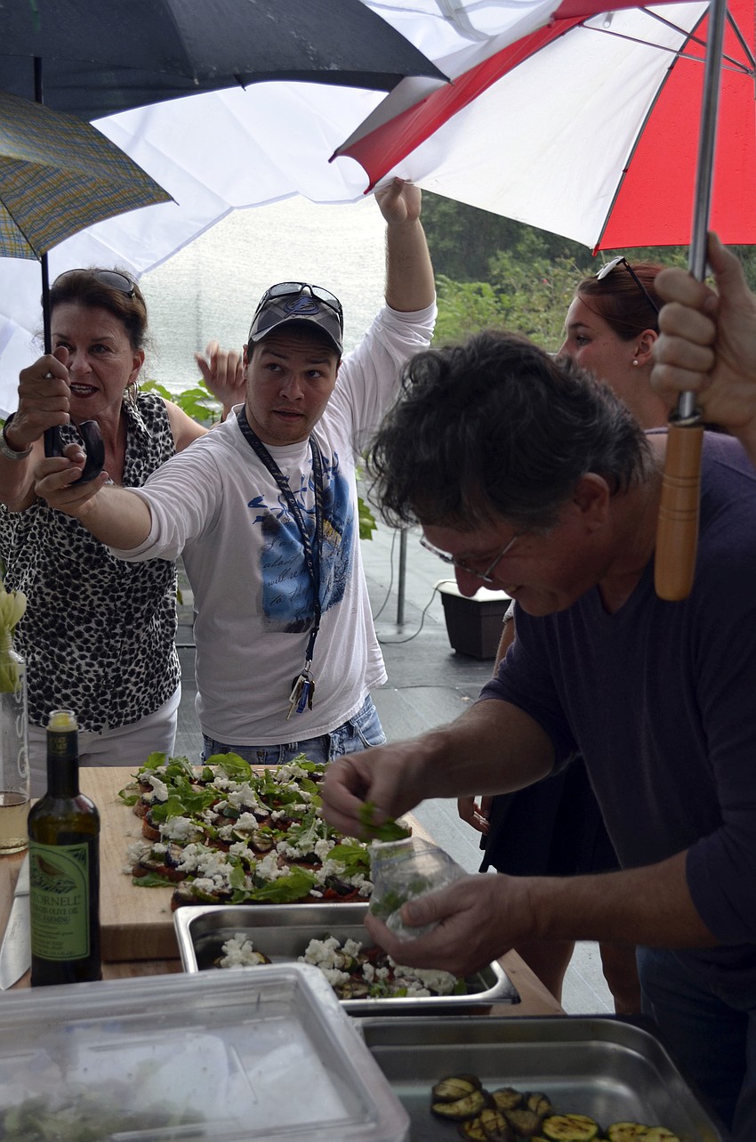 Students cover Chef Martinez as he finishes preparing lunch in the rain.