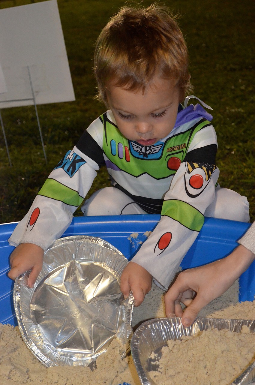 Landon Ranck, or Buzz Lightyear, digs for coins in a sandbox.
