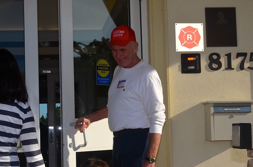 Election Day volunteer Marty Kristo reminds voters to have photo identification ready.