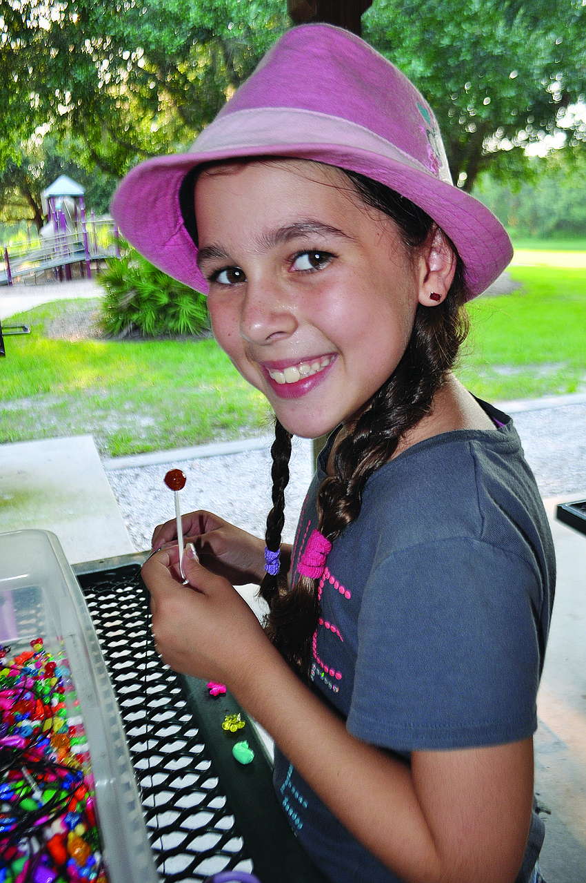 Jenna Link, 8, makes a bracelet at Temple Emanu-El's havdalah ceremony and gathering at Summerfield Park.