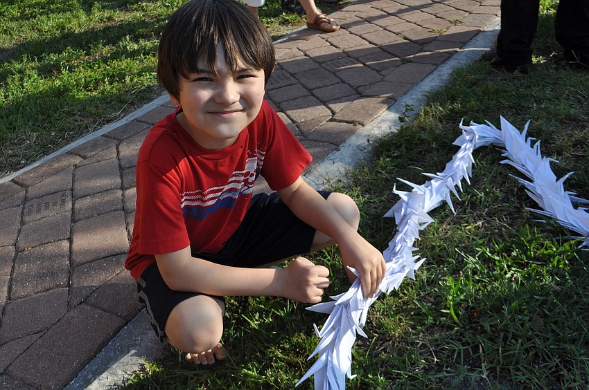 Jake Taylor, 9, touches a loop made of 1,000 origami paper cranes for good luck.