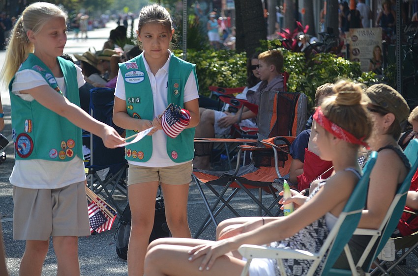 Brooklyn Cline and Dorianne Krizen of Girl Scout Troop 506 hand out flags.