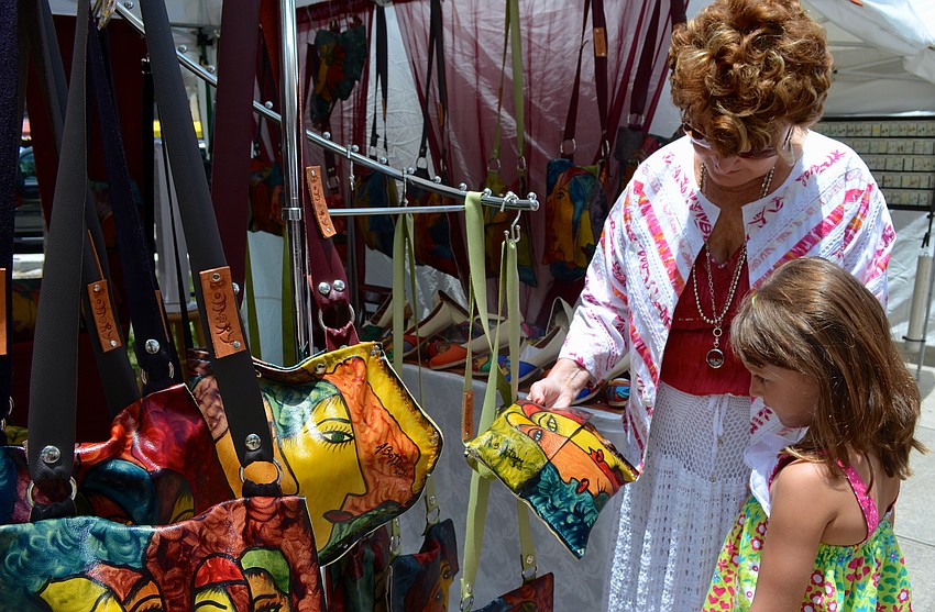 Ginny Bogue and her granddaughter, Madison Bogue, browse the purses at Adriana Bottaryâ€™s leather booth.