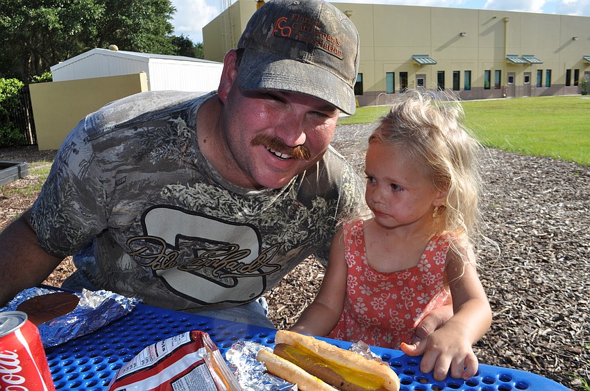 Dale and Riley Koch find a shady spot at the playground to eat dinner.