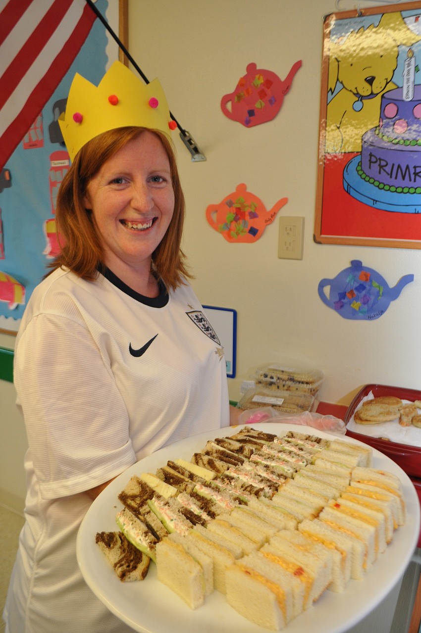Teacher Grace McGrath, a native of England, serves finger sandwiches to her class as it celebrates England.