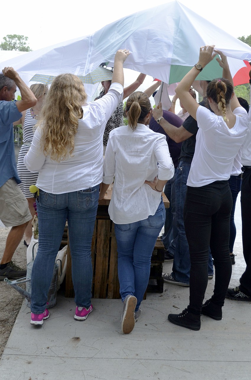 Students cover Chef Martinez as he finishes preparing lunch in the rain.