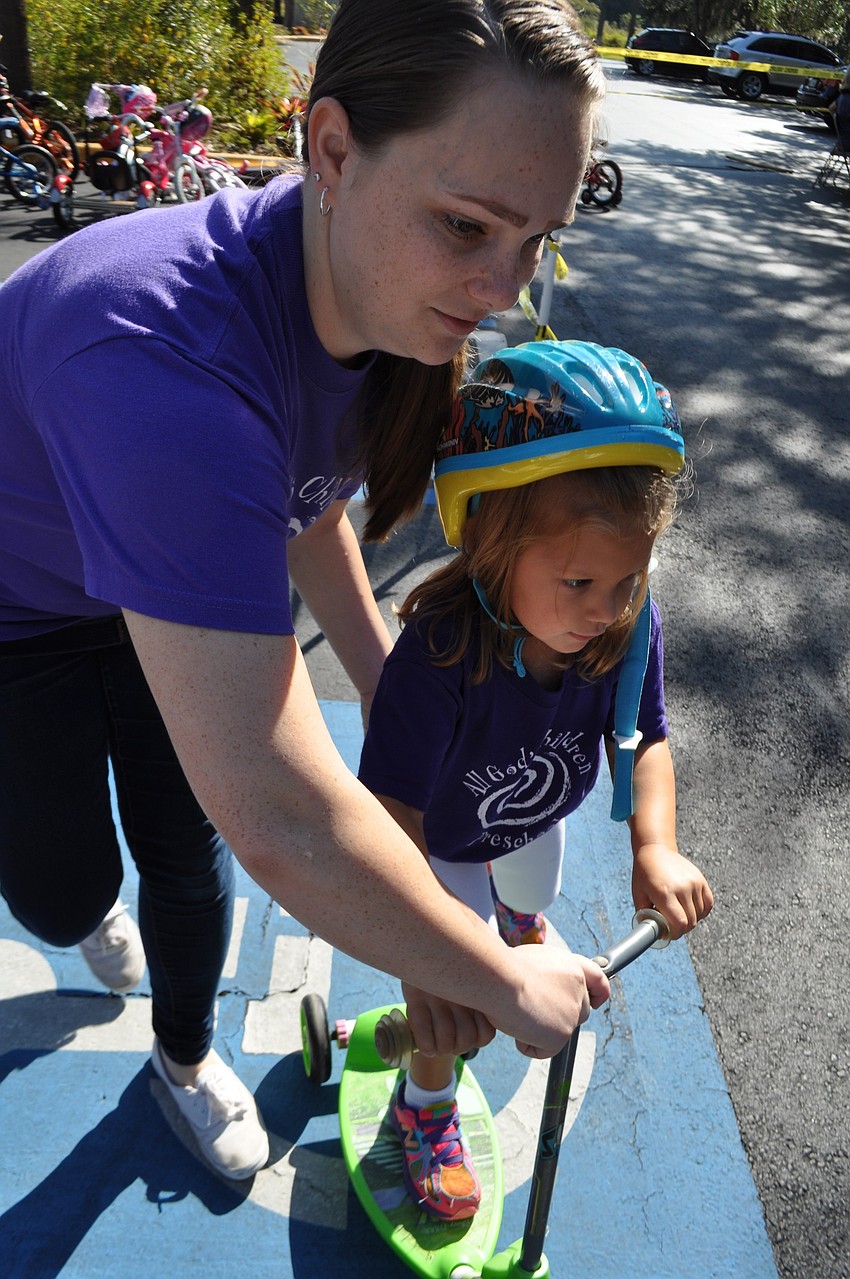 Kathryn Nahrwold helps Grace Monserez mount her scooter.