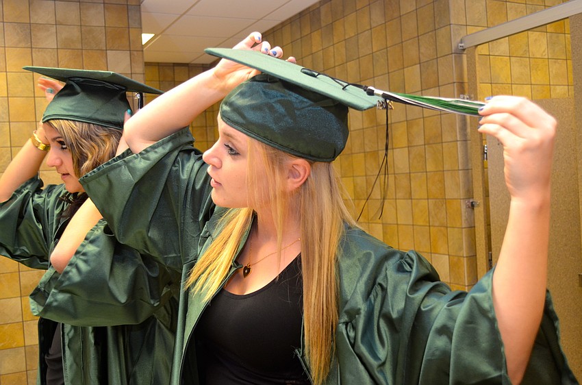 Alison Miller and Kayla Mathews adjust their caps and gowns.