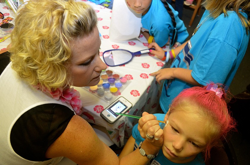 Cynthia Hoeksema paints Grace Wortley's face.