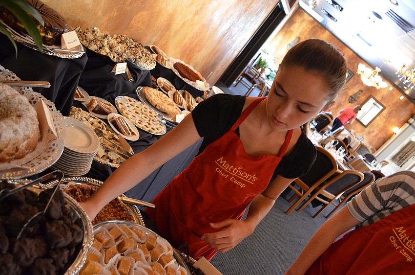 Kendall Peacock places name cards for each of the desserts the campers made
