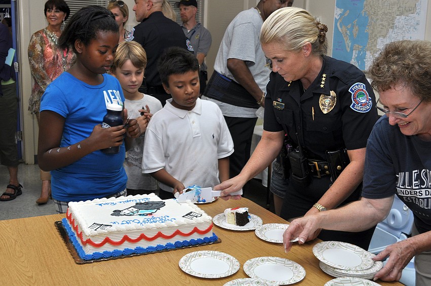 Chief of Police Bernadette DiPino cuts slices of cake for the guests at National Night Out Against Crime.