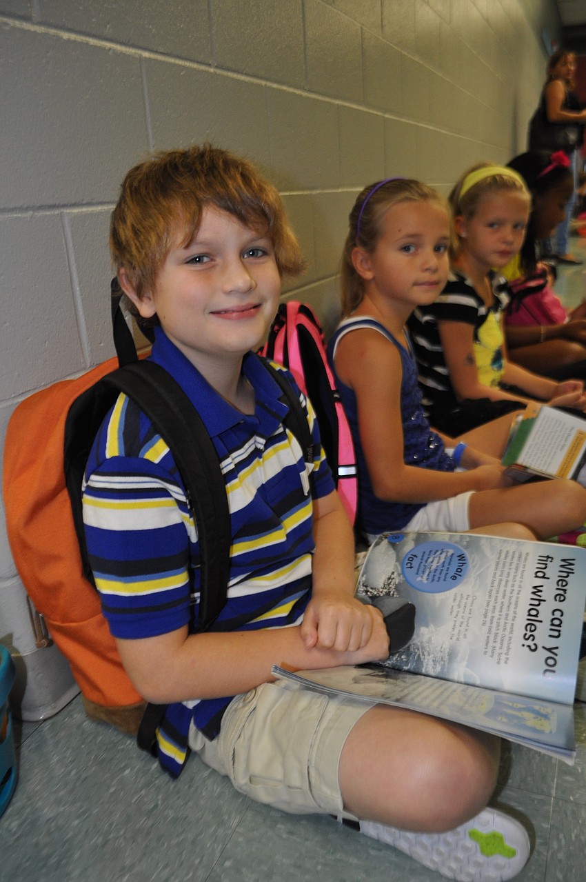 William Cooper, 8. reads a book on whales while he waits for school to start.