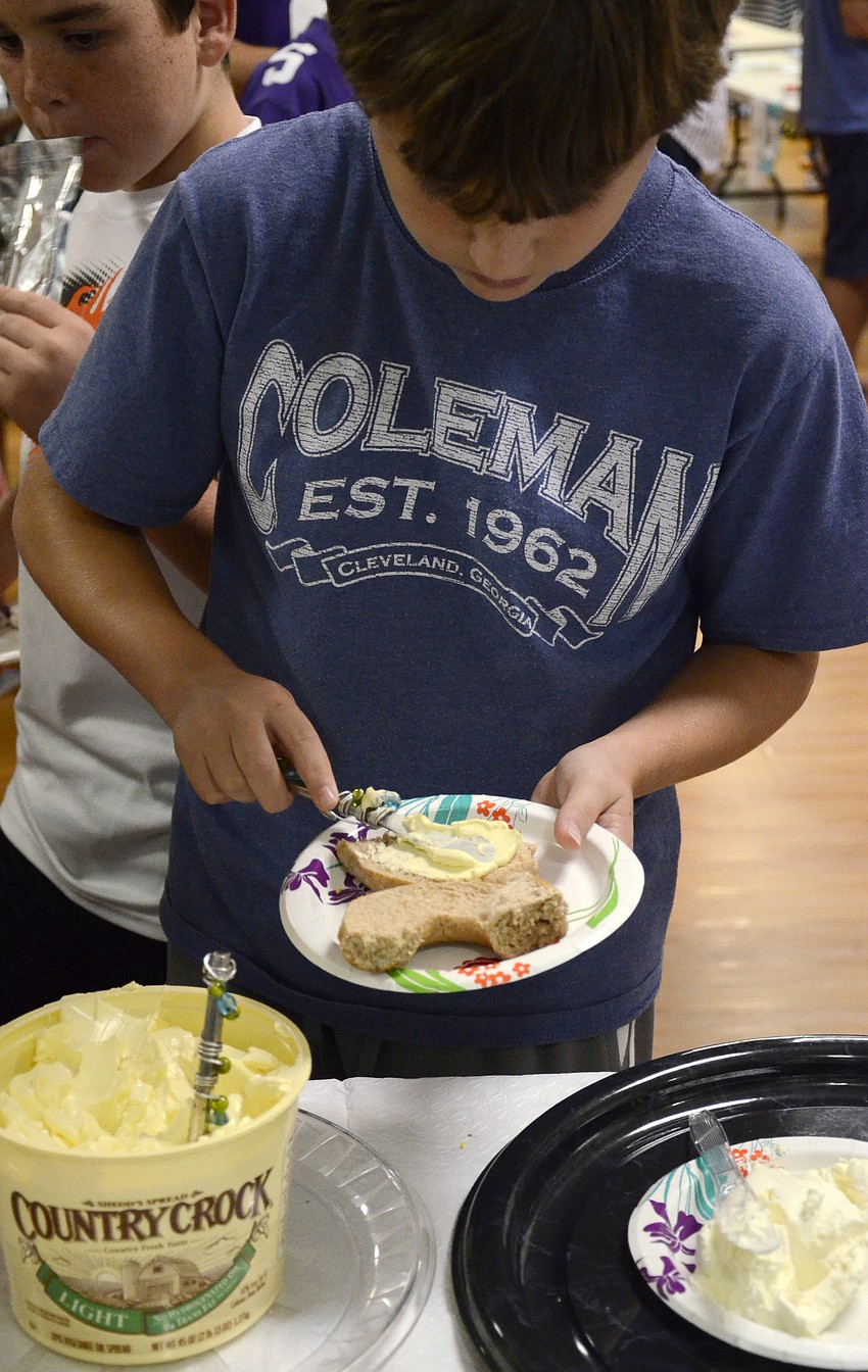 Ben Baram, 10, adds some butter to his bagel after the Temple's religious class orientation Sunday.