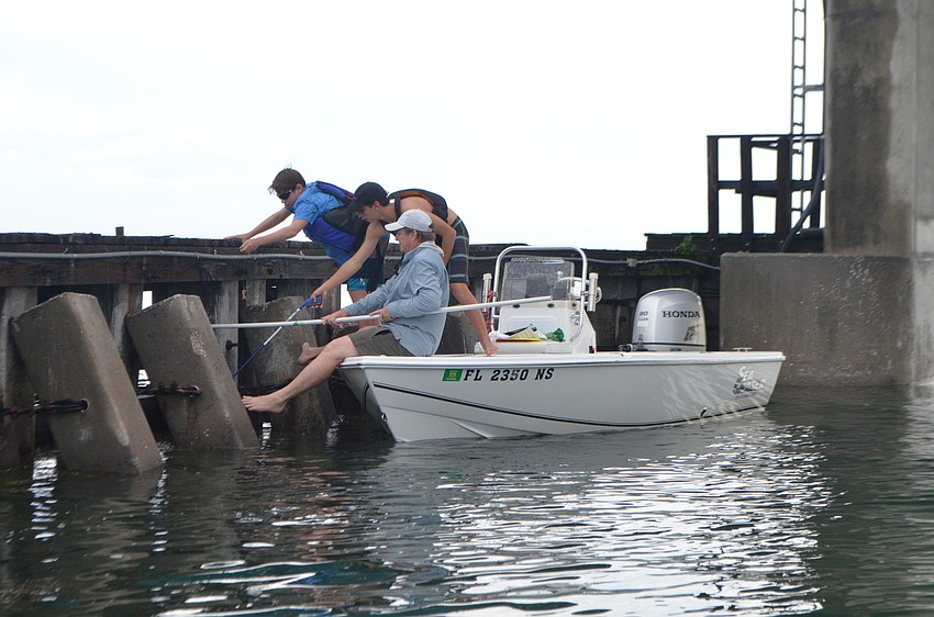 Steve Traves, Skye Ehrhart, 15, and Wyatt Kaighin, 12, clean up fishing equipment beneath the New Pass Bridge on the south side of Longboat Key.