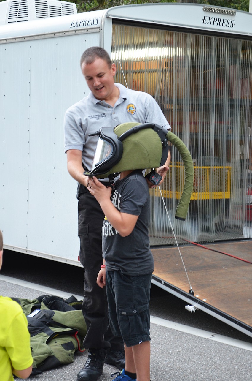 Officer Adam Morningstar of the Explosives Materials Unit assists Xavier Arteaga with trying on the blast suit.