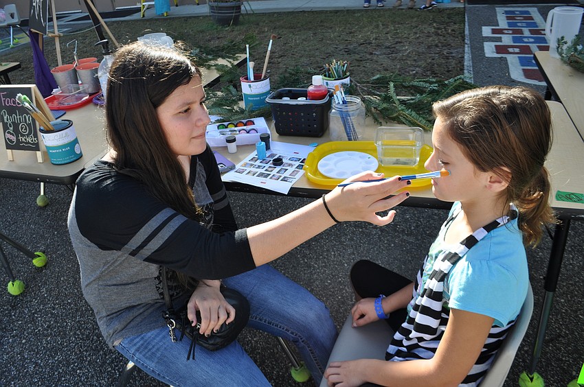 Claudia Fedroff paints a mask on the face of Kaley Kennedy, 9.