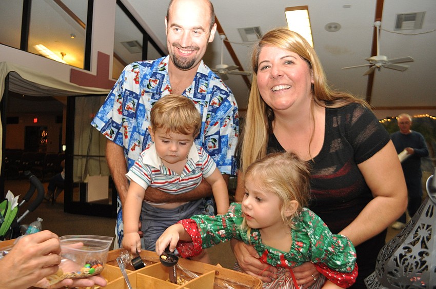 Kersten and Wendi Schroeder hold their children, Mikey and Braelyn, as they select nuts and other snacks at a both.