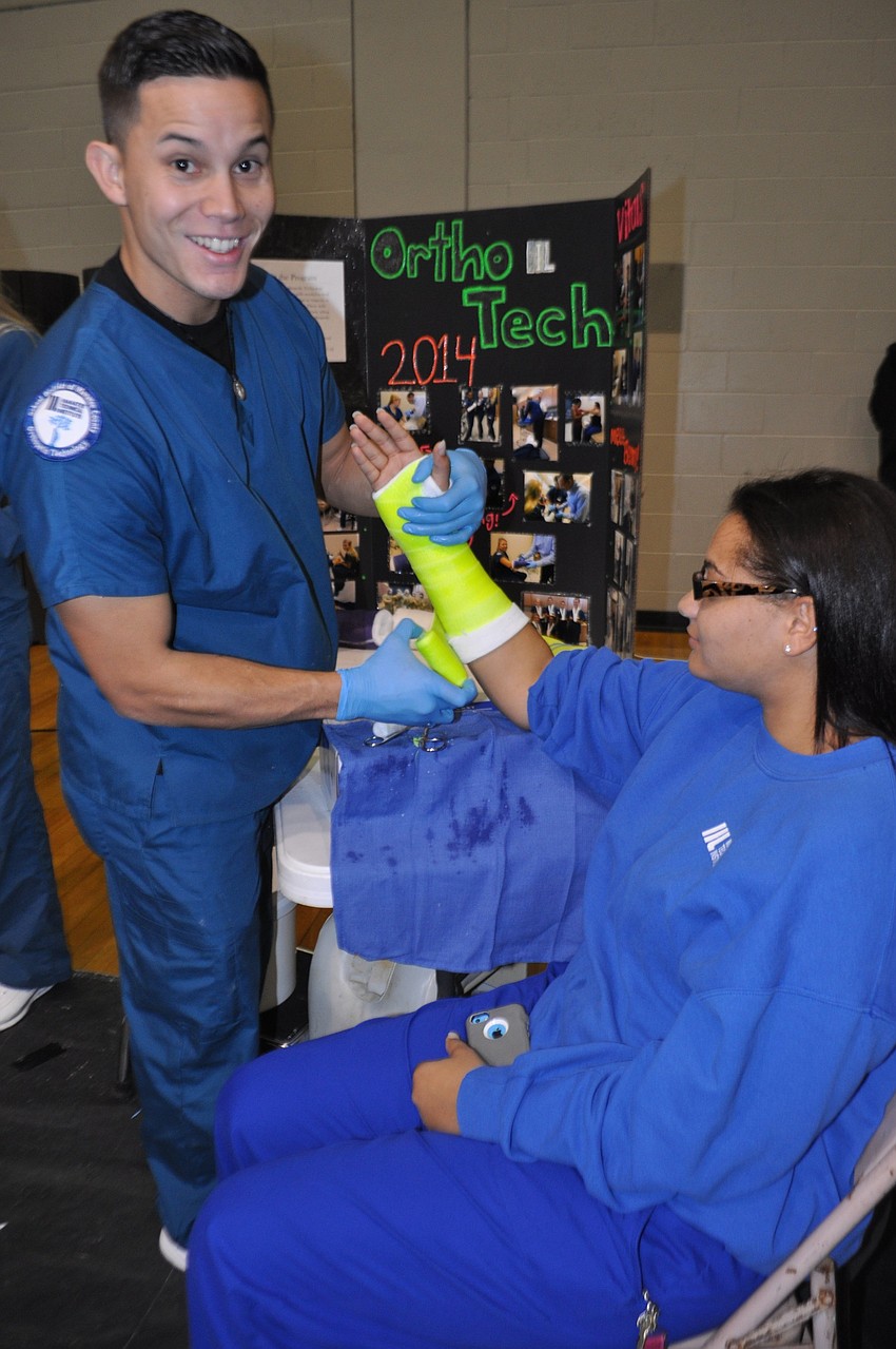 Manatee Technical College student Jerome Quiming demonstrates how to create a fiberglass short arm cast with the held of fellow MTC student Christina Glover, in the patient care technology program.