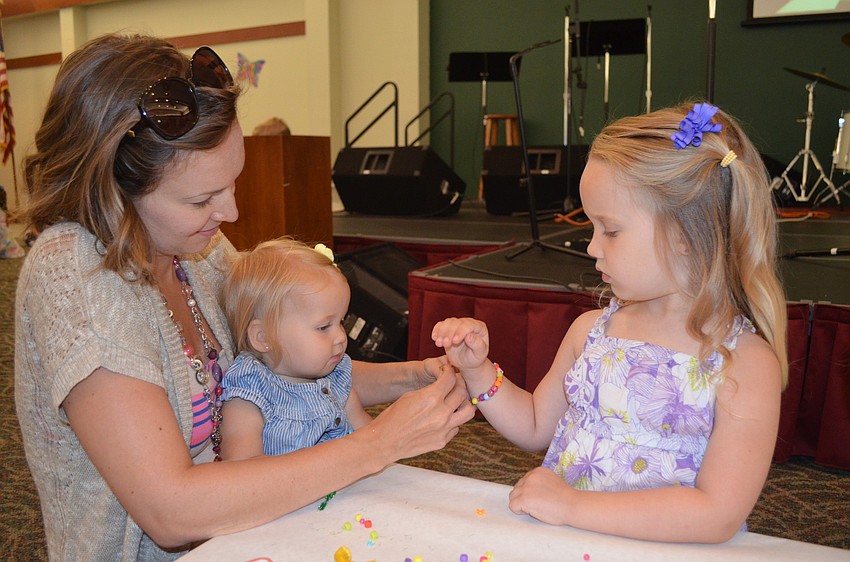 Kelly, Piper and Lily Rowe make a bead bracelet.