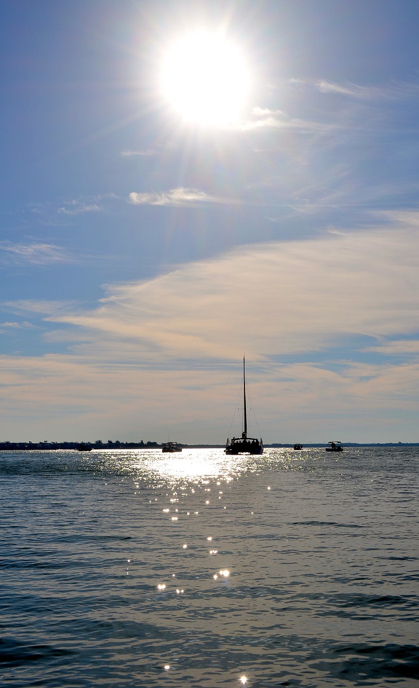 A catamaran, along with a few smaller boats, takes volunteers to Sister Keys.
