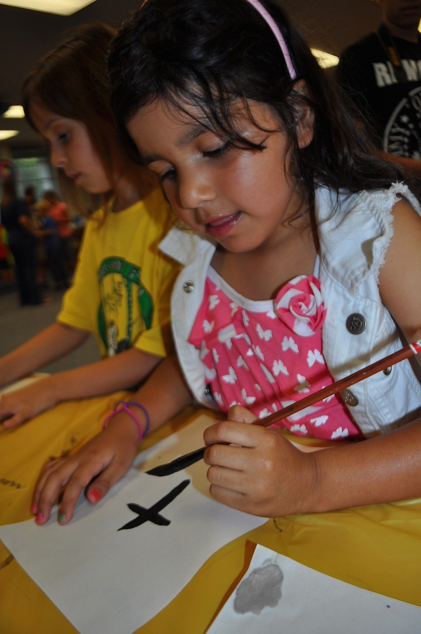Claudia Veronica Vicarro, 6, paints the Chinese word for tree.