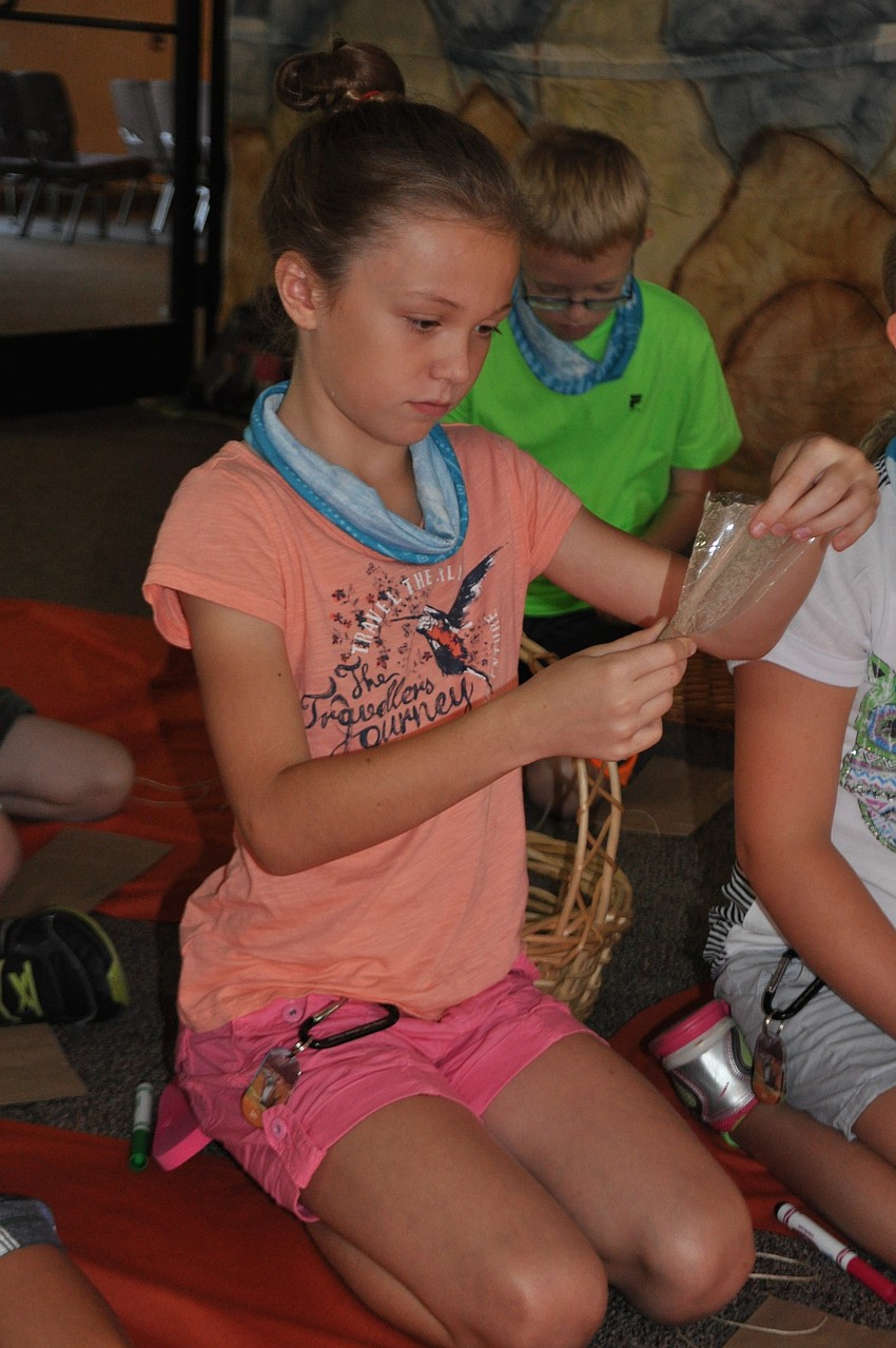 Wesly Viquerat, 9, makes a necklace out of clay and string.