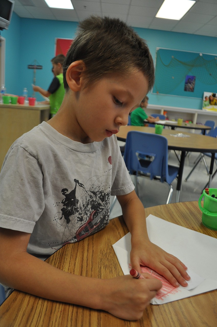 Lucas Kilpatrick, 7, decorates a paper airplane.