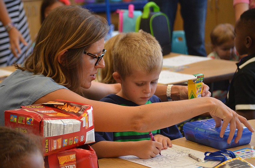 Kim McKay helps son, Liam, get settled in to his new desk for Kindergarten.