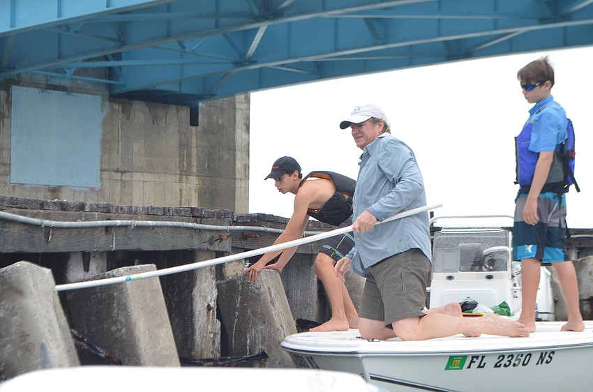 Steve Traves, Skye Ehrhart, 15, and Wyatt Kaighin, 12, collect monofilament and other waste beneath New Pass Bridge, a common spot for birds.