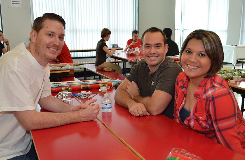 Jeremy Schweickert, Bill Oâ€™Brien and Josie Ludrigue all pitched in to help gift wrap at Girls Inc.