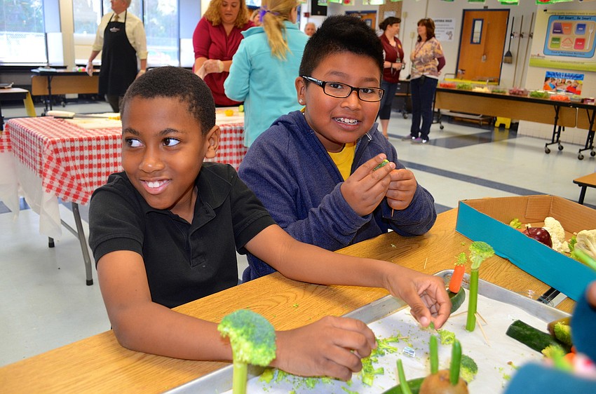 Edrick Choute and Selestino Sanchez make trees out of broccoli for their project.