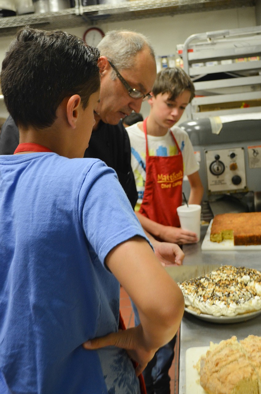 Chef Ray Lajoie shows Jay Piare (left) and Elvin Dekok (right) how to best cut and serve a pie.