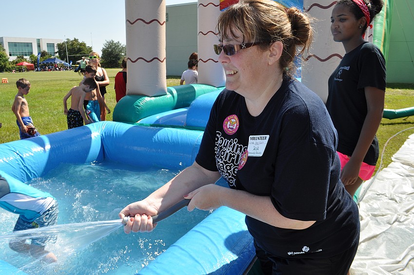 Volunteer Linda Harrell sprays children with water.