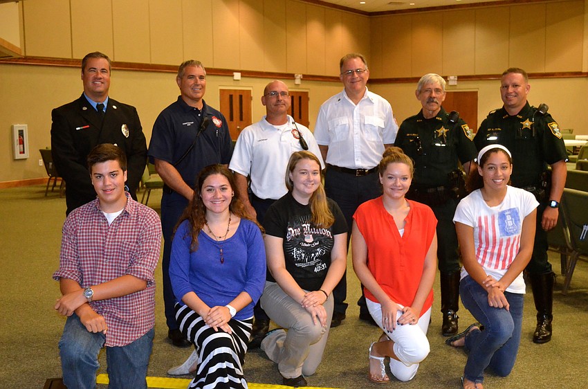 Providence Community School's National Honor Society smiles beside firefighters and law enforcement officials.