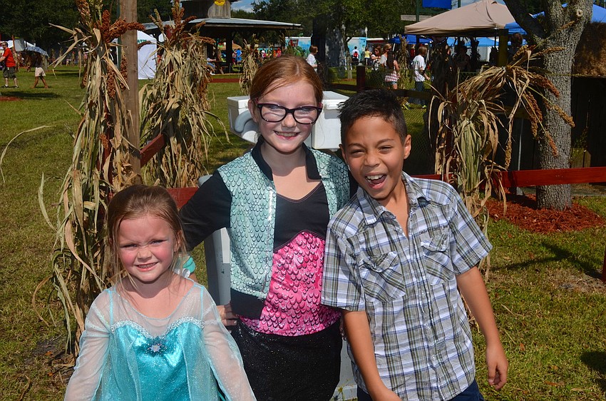 Riley and Autumn Bodenweiser show off their Halloween costumes beside Yaxel Benejam.