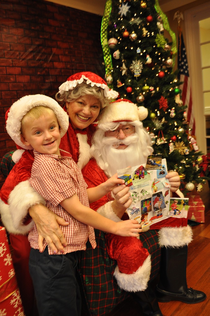 Five-year-old Caden Parker brings Mrs. Claus and Santa, portrayed by Jeanne and and John Larranaga, a list that includes pictures of desired items.