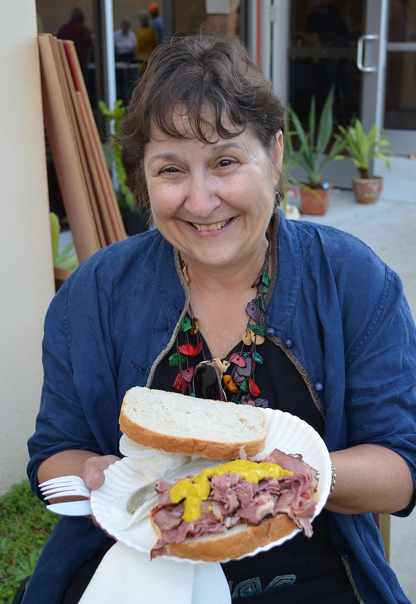 Ann Lugbill tries a pastrami sandwich with mustard.
