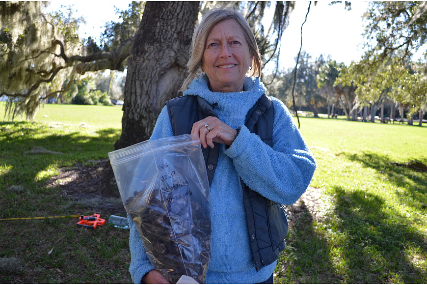 Volunteer Roxanne Williamson holds up a 10-pound bag of shells found on the grounds of Phillippi Estate Park.