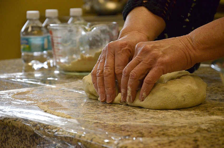 Sonja Carpenter connects the ends of the dough roll to form the shape of the king cake.