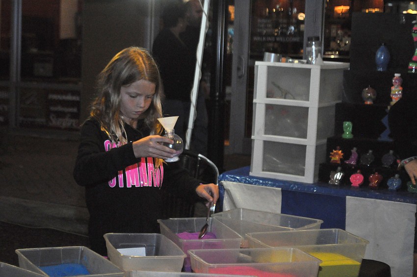 Skyler Czaja of GreyHawk Landing makes a sand art piece at the Family Fun Entertainment tent.