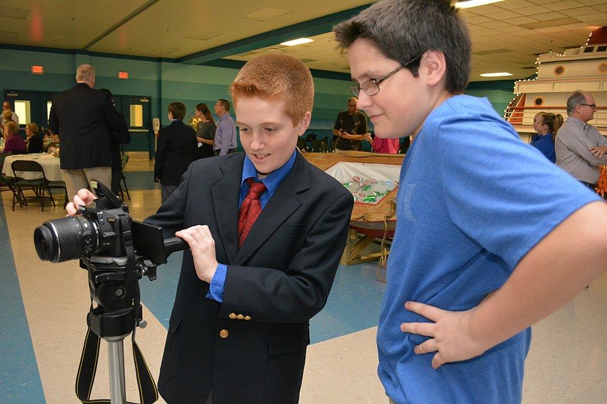 Griffin Hudson video tapes guests as his friend, Braden River High School student Devon Summerville, watches.