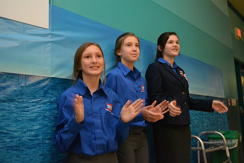 TSA students Miranda Davis, Carlie Phelps and Jordan Brown clap during a video presentation.