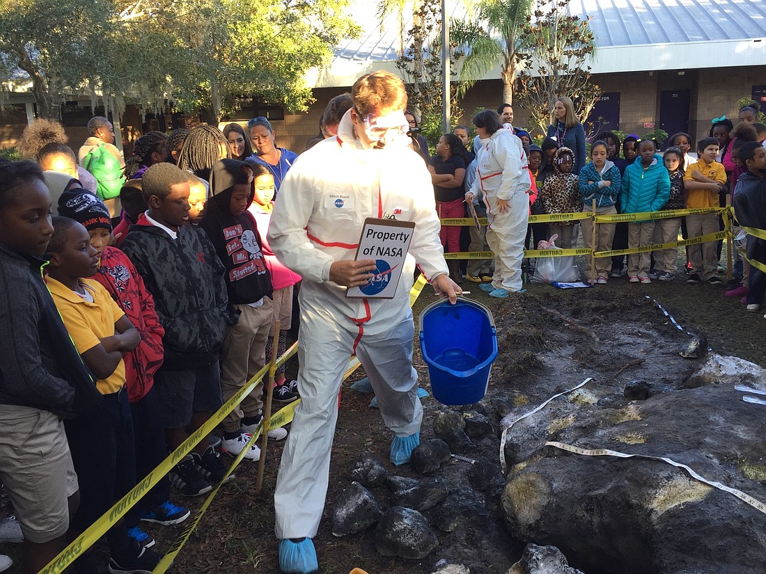 Courtesy of Suncoast Science Center. Mitch Ruzek examines the mystery meteor that landed on campus at Emma Booker Elementary School Monday, Jan. 11.