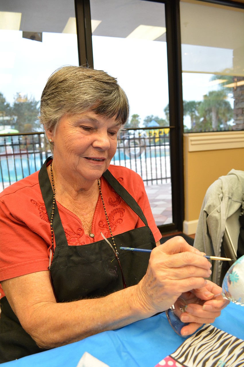Judy Arras paints flowers on her wine glass.