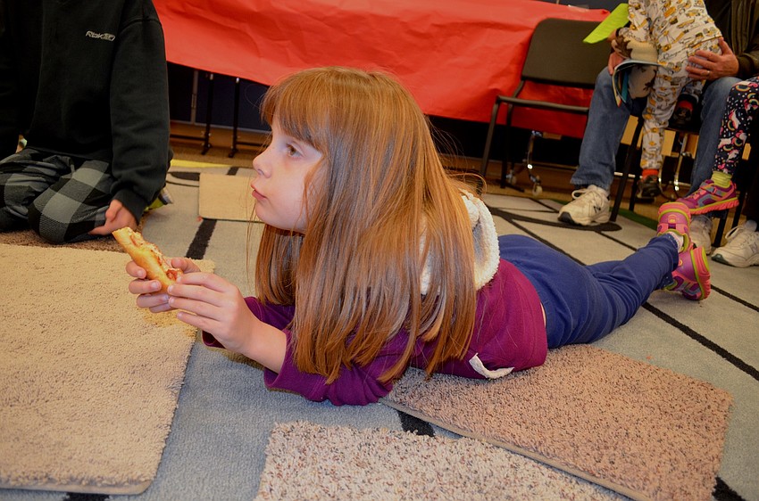 Kimberly Lavick, a kindergarten student, snacks on pizza and enjoys story time.