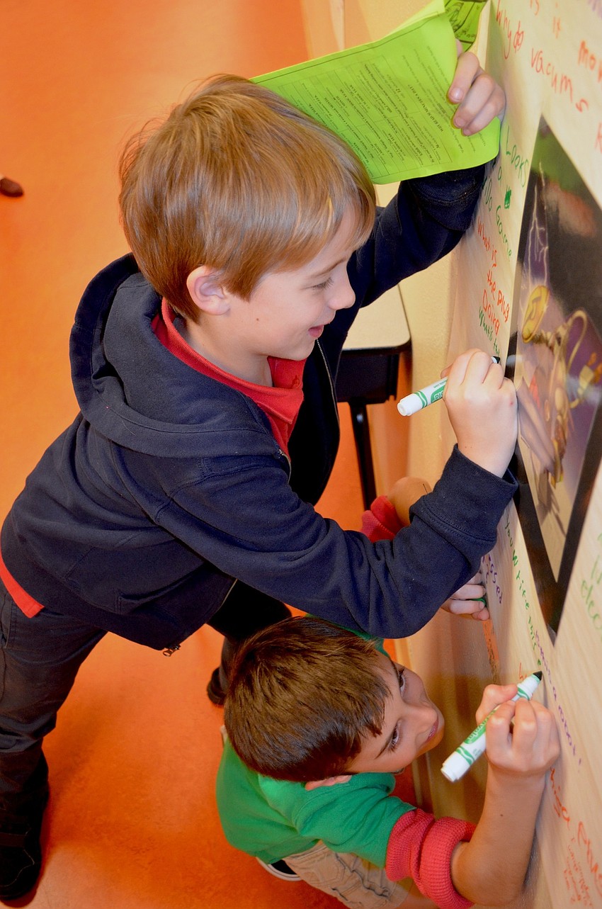 P.J. Jackson and John Emoposimto draw funny pictures on a dry-erase board.