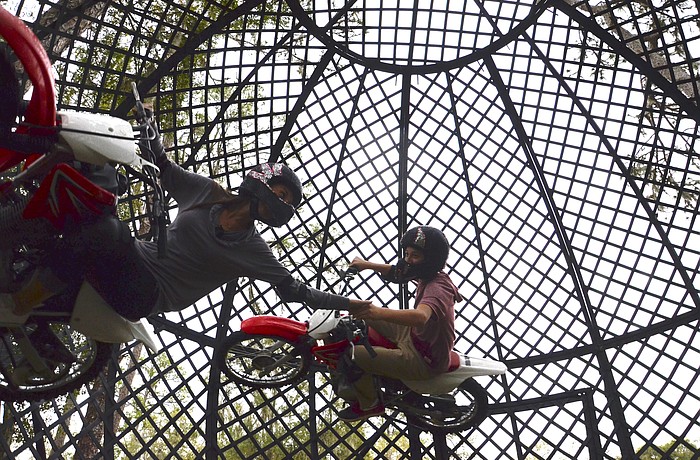 Cyndel Flores reaches to grasp her brother's hand as they spin around the Globe of Death.